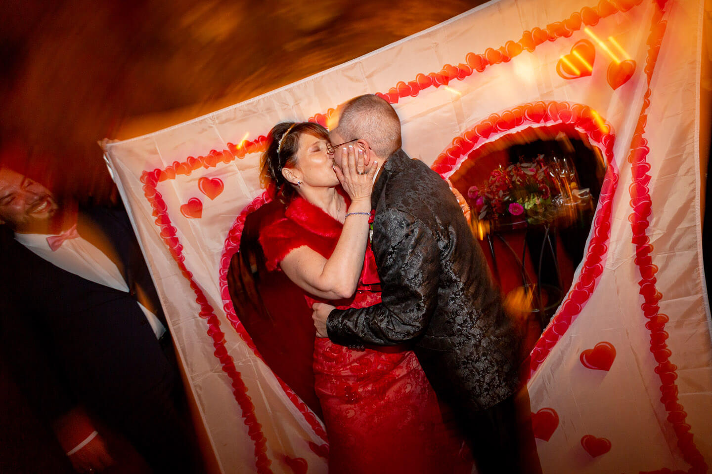 Brautpaar schreitet durch das ausgeschnittene Herz eines Bettlakens