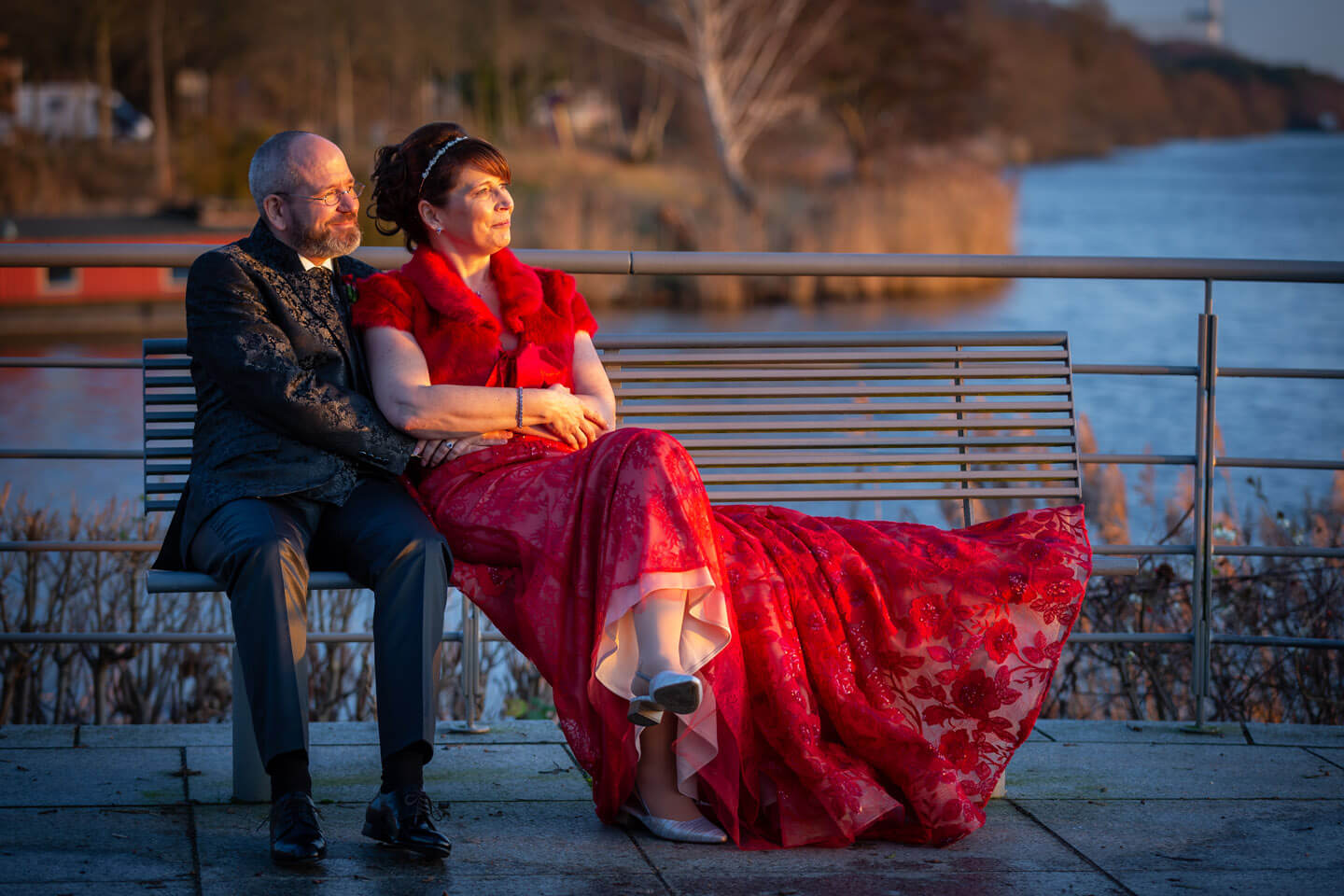 Hochzeitspaar auf einer Parkbank im Sonnenuntergang an der Elbe