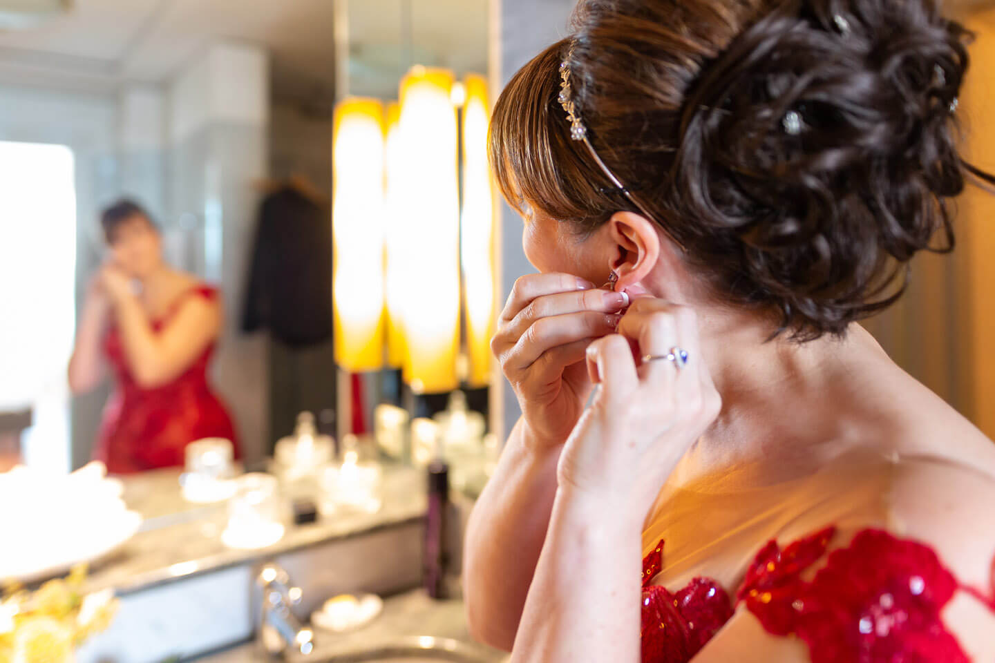 Braut legt Ohrringe vor dem Spiegel an.