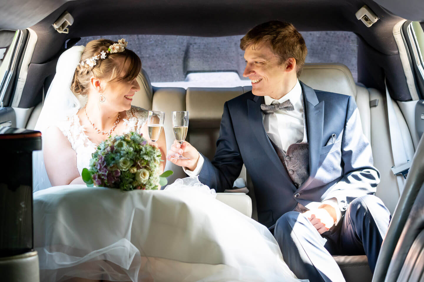 Brautpaar trinkt ein Glas Sekt im Hochzeitsauto