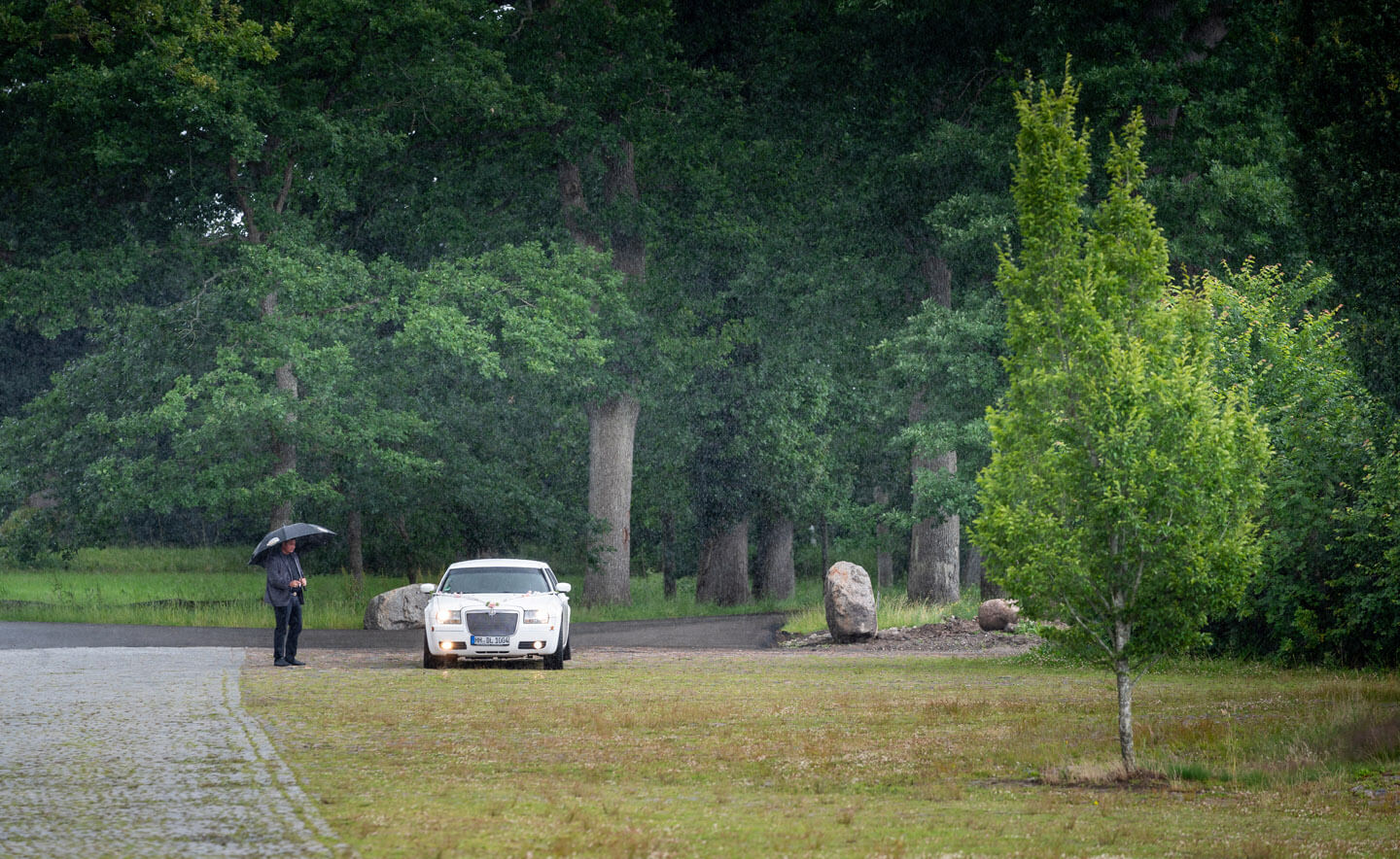 Limousine mit Hochzeitspaar steht im Regen