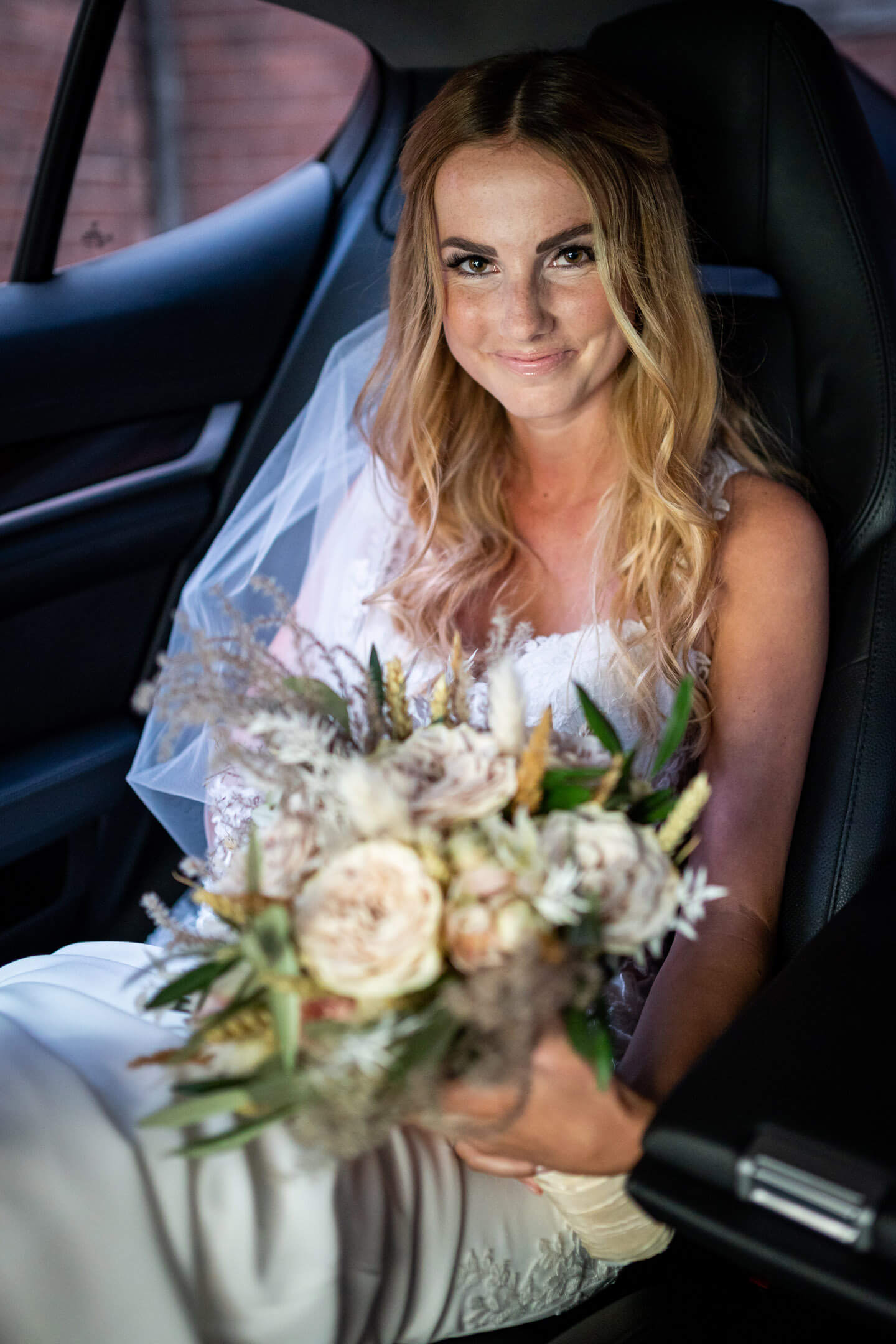 Braut sitz mit ihrem Brautstrauss im Auto und wartet auf die Hochzeit in Buxtehude