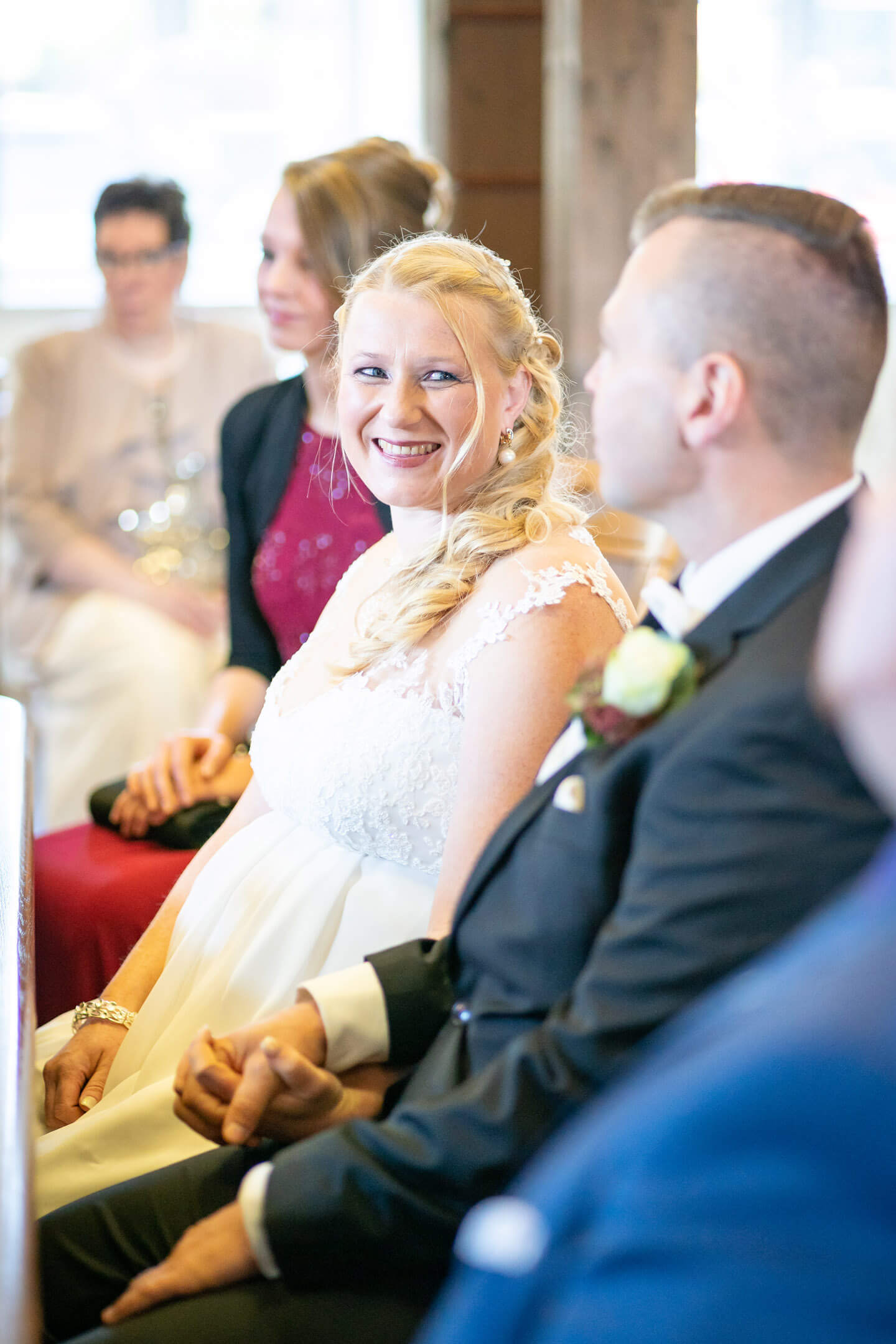 Braut blickt Bräutigam bei der Trauung lachend an.