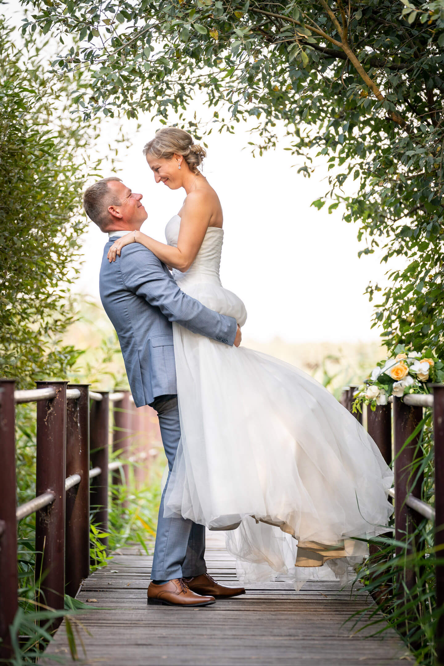 Auf Händen getragen: Bräutigam hebt seine Braut hoch.