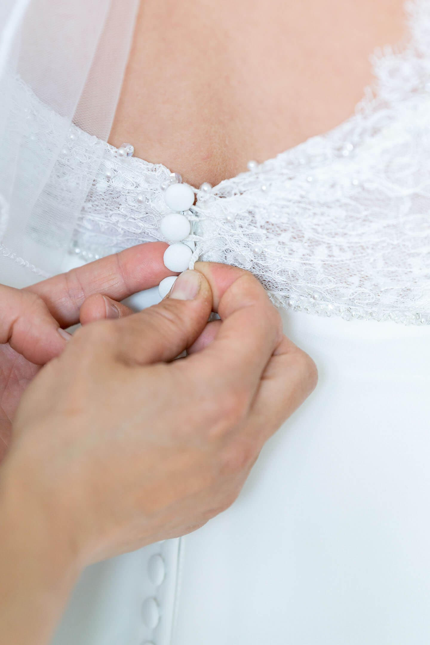 Brautkleid wird zugeknöpft.