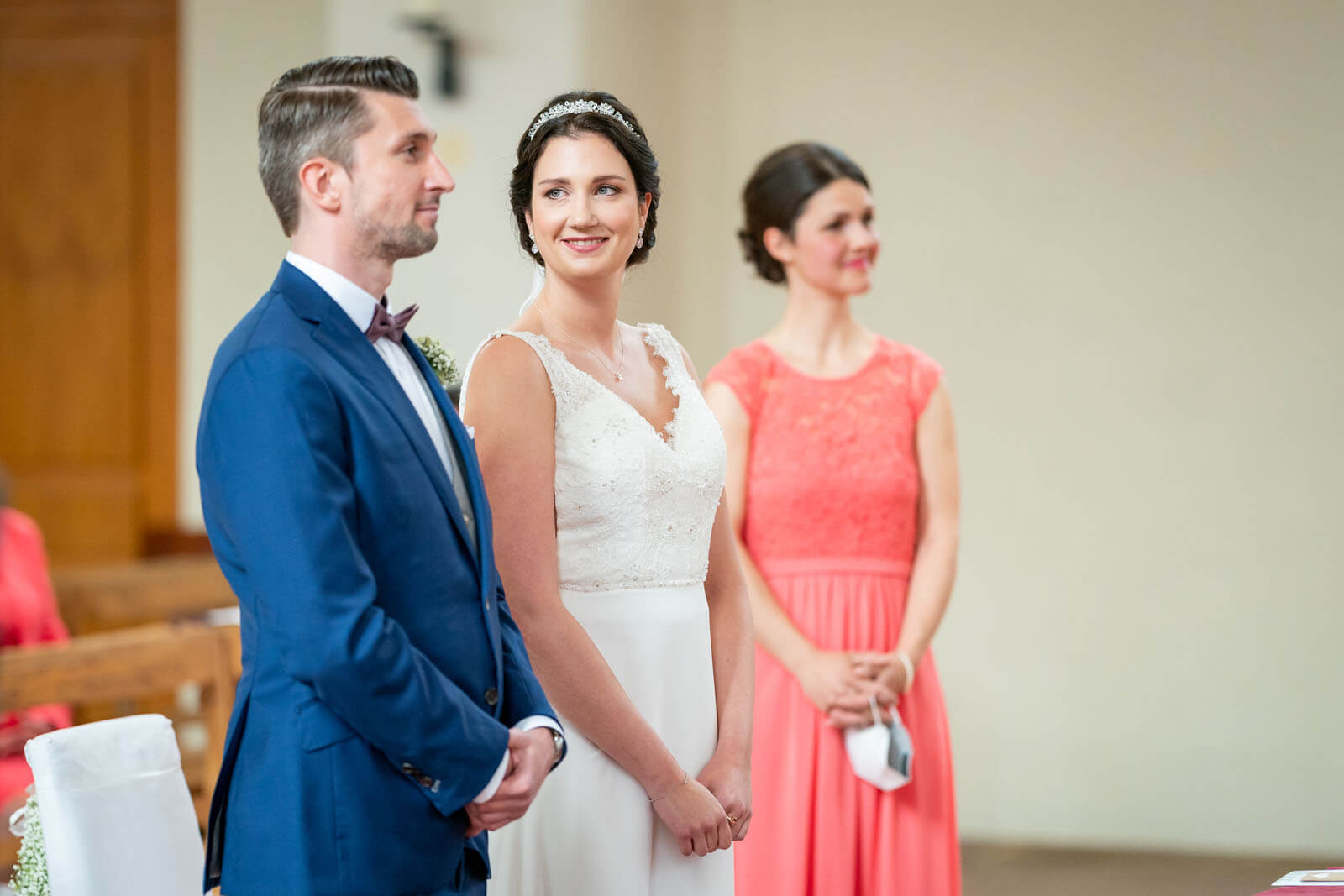 Brautpaar und Trauzeugin vor dem Altar.