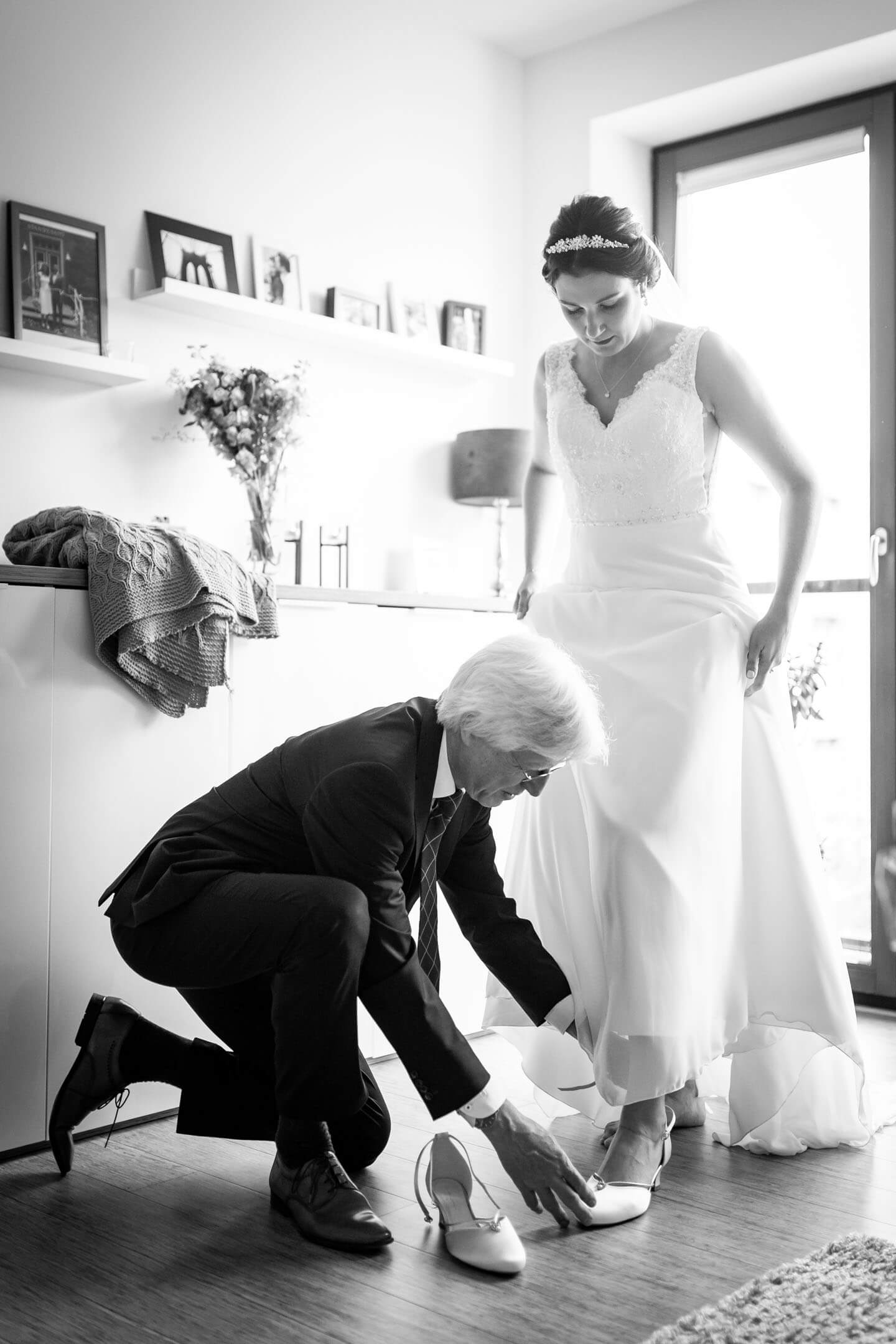 Brautvater zieht der Braut die Hochzeitsschuhe an.
