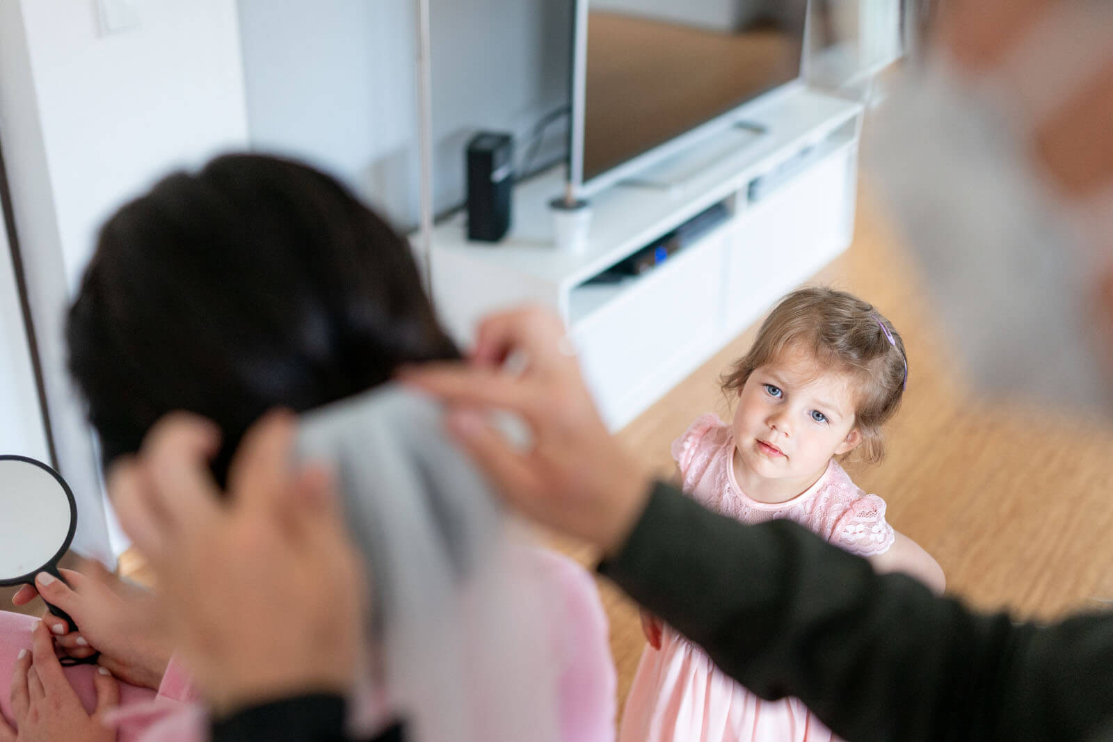 Blumenkind schaut beim Styling der Braut zu.