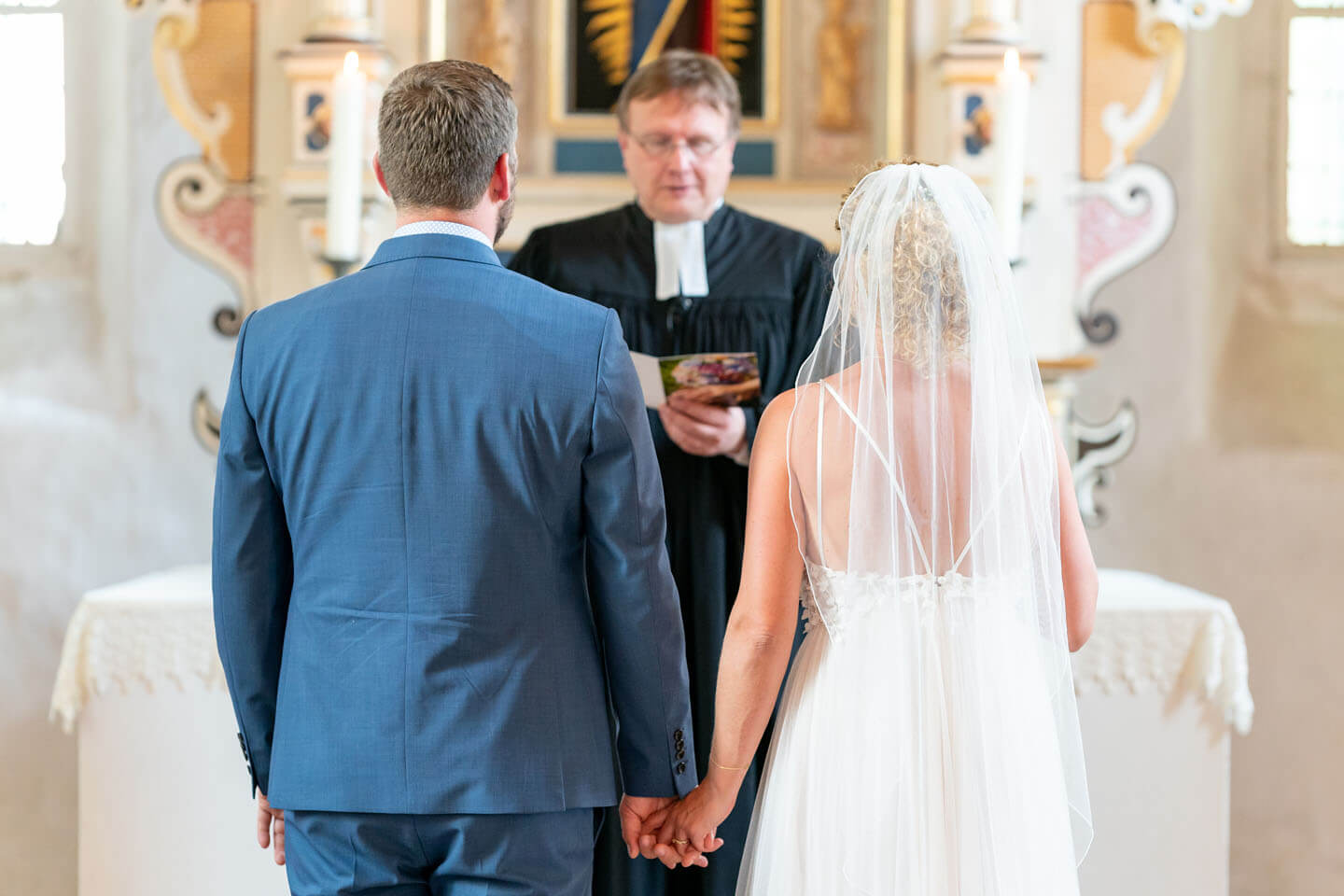 Hochzeitspaar vor dem Altar mit Pastor beim Traugottesdienst