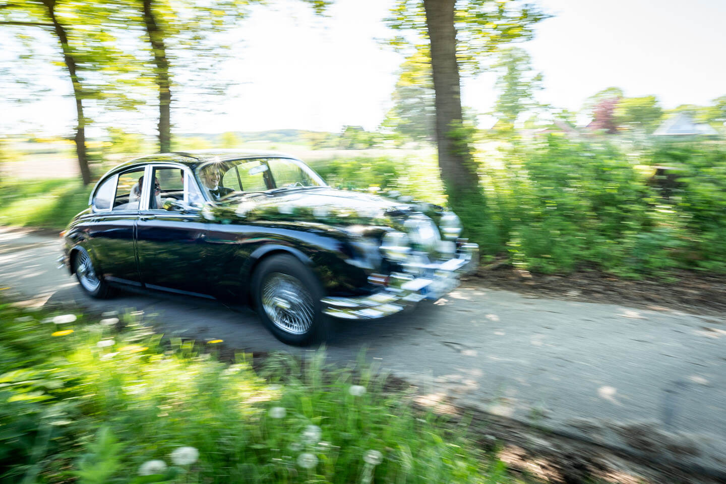 Hochzeitsauto düst durch einen Feldweg.