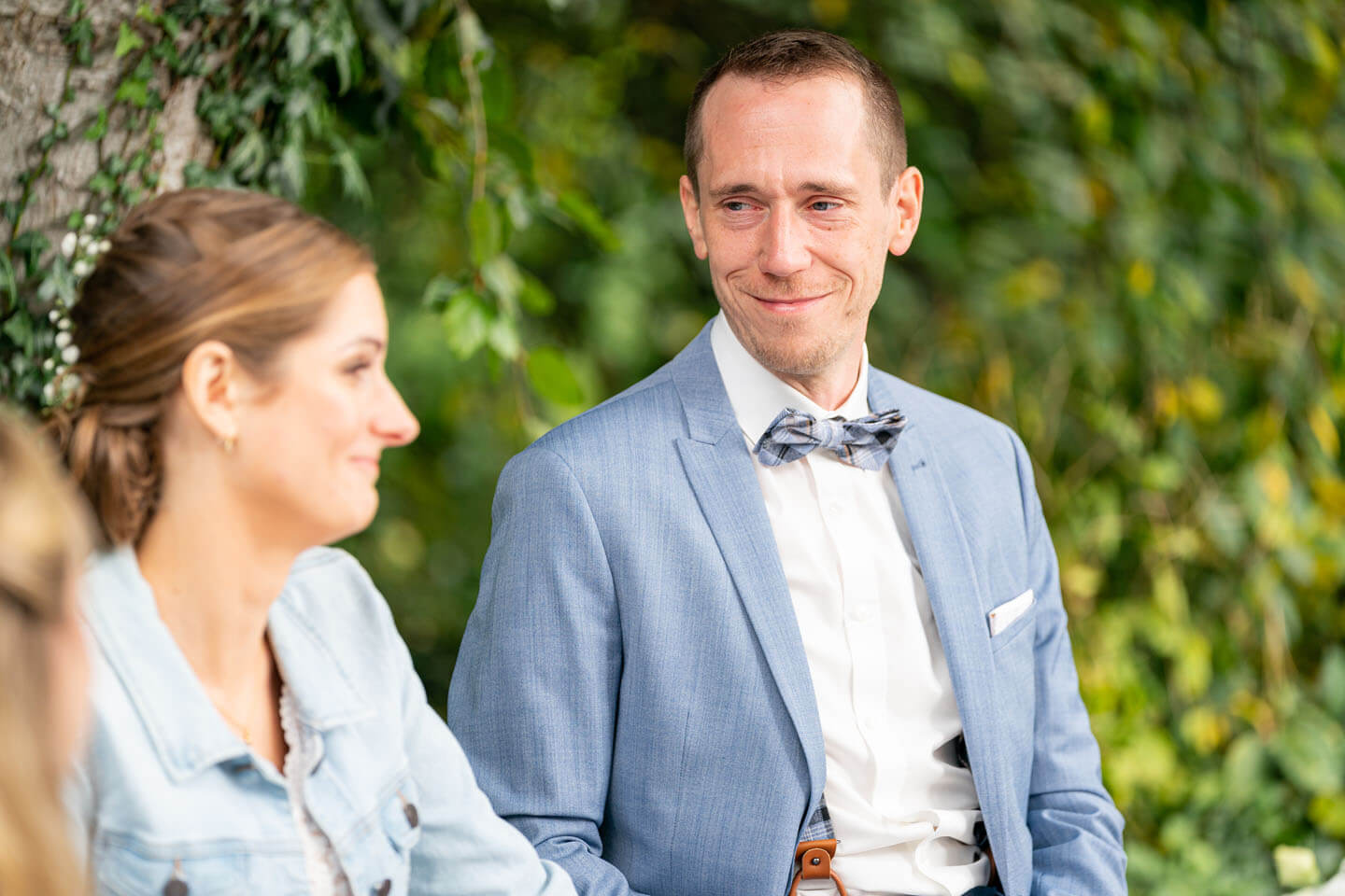 Bräutigam blickt Braut bei Trauung unter dem freien Himmel an
