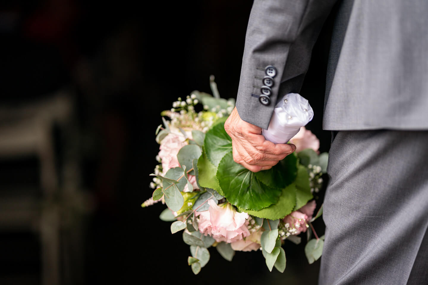 Brautvater hält den Brautstrauß in der Hand.