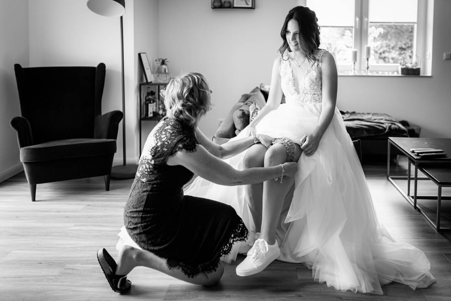 Brautmama zieht der Braut das Strumpfband an.