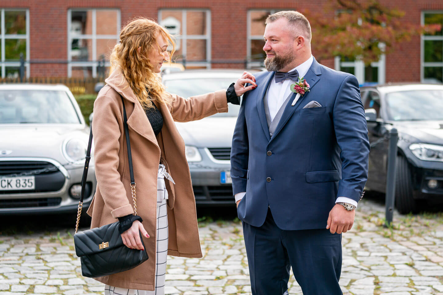 Trauzeugin nimmt den letzten Fusel vom Anzug des Bräutigams.