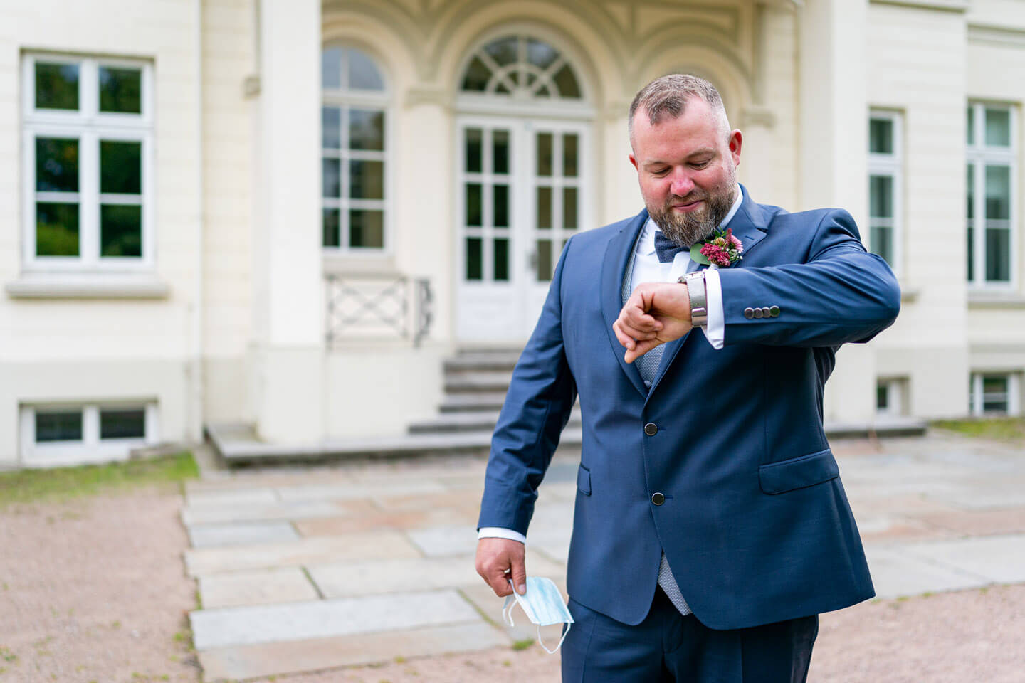Der Bräutigam schaut vor dem Berner Schloss auf die Armbanduhr.