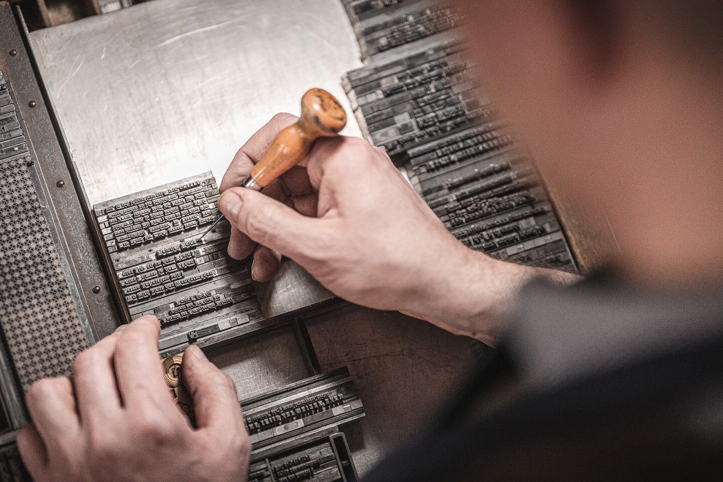 Schriftsetzer bei der Arbeit über die Schulter fotografiert.