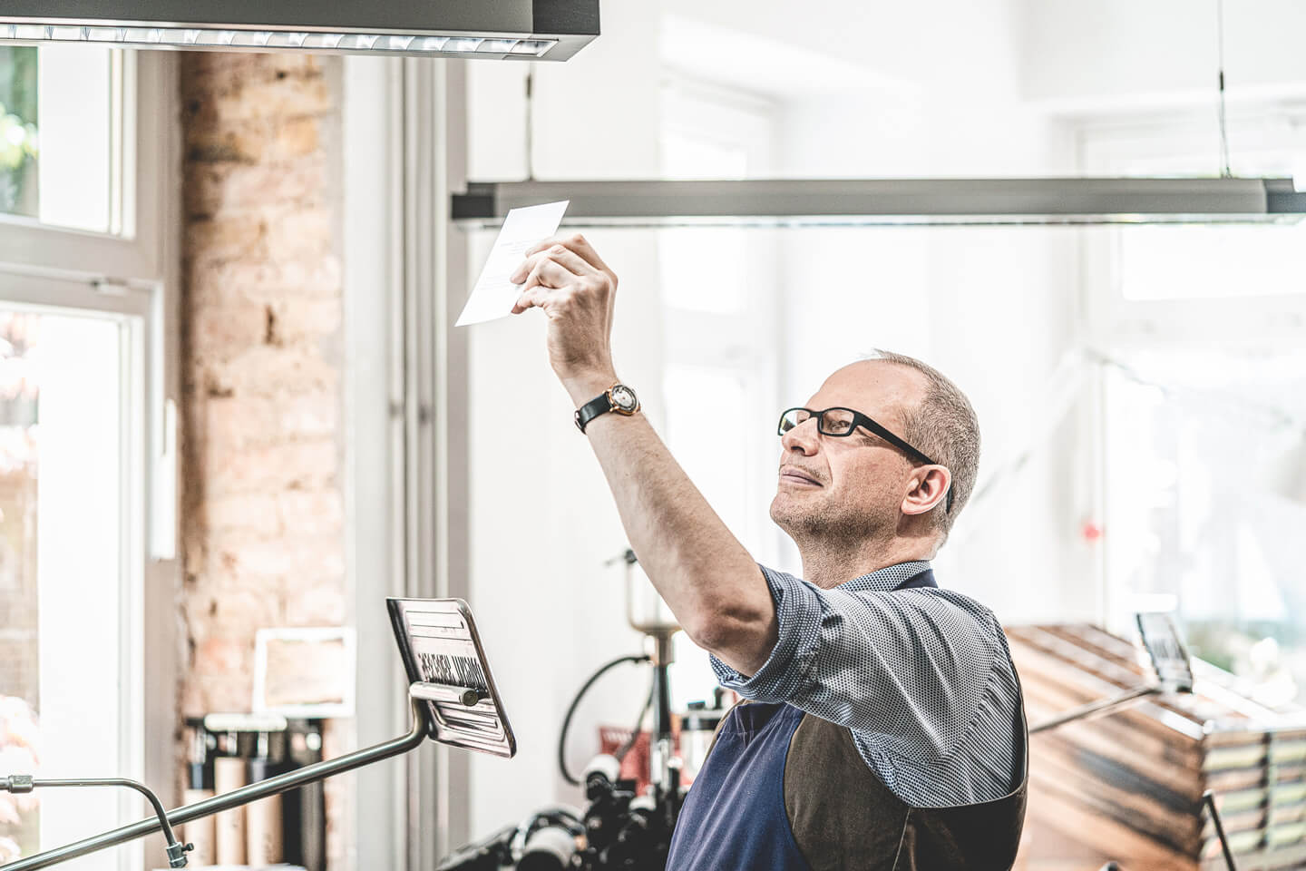 Drucker betrachtet das Papier im Gegenlicht