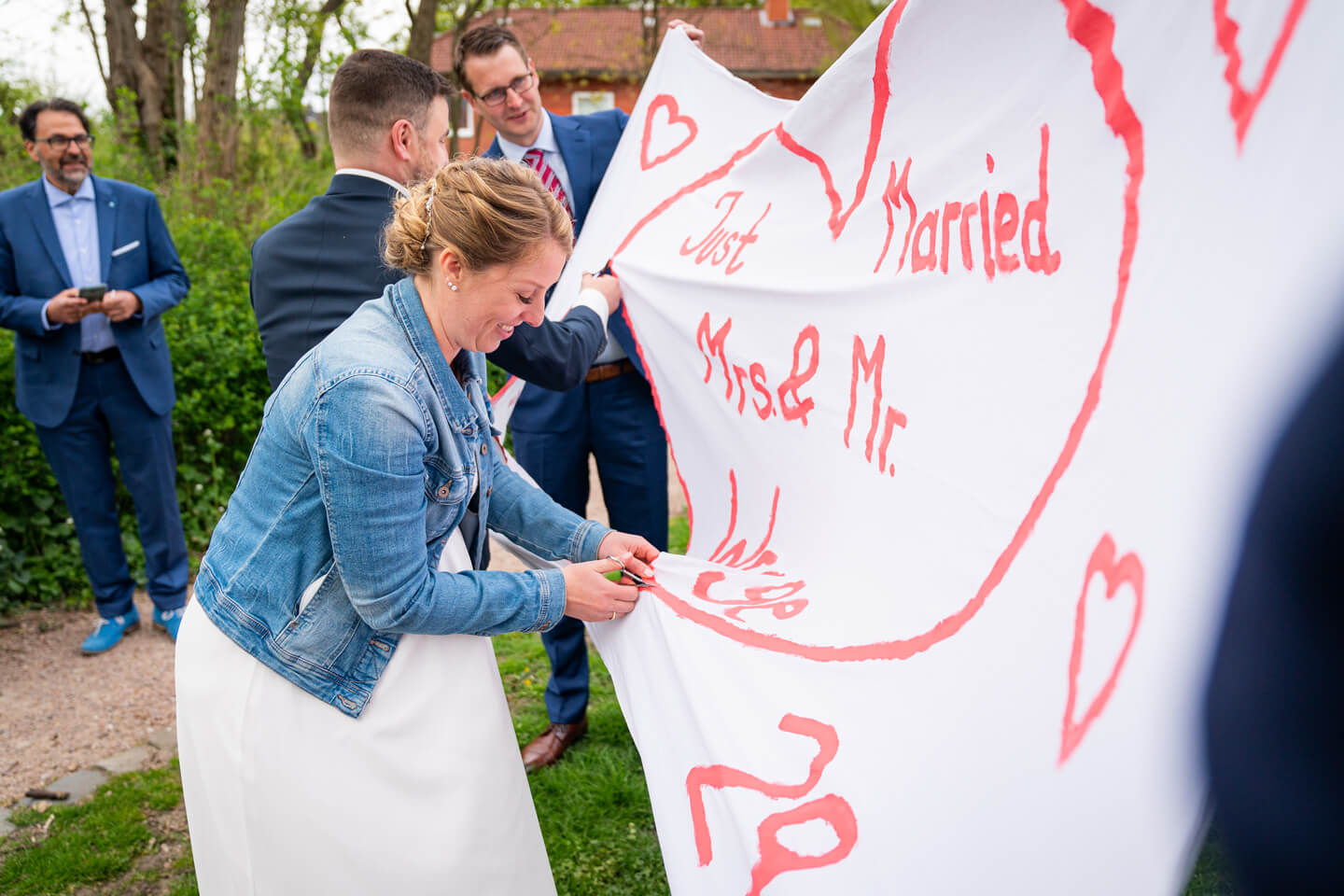 Brautpaar schneidet Herz aus Bettlaken aus.