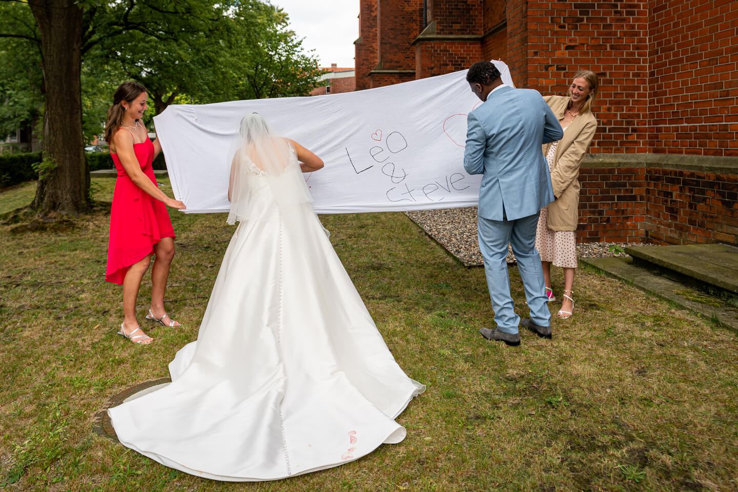Hochzeitspaar schneidet Herz aus Bettlaken aus.