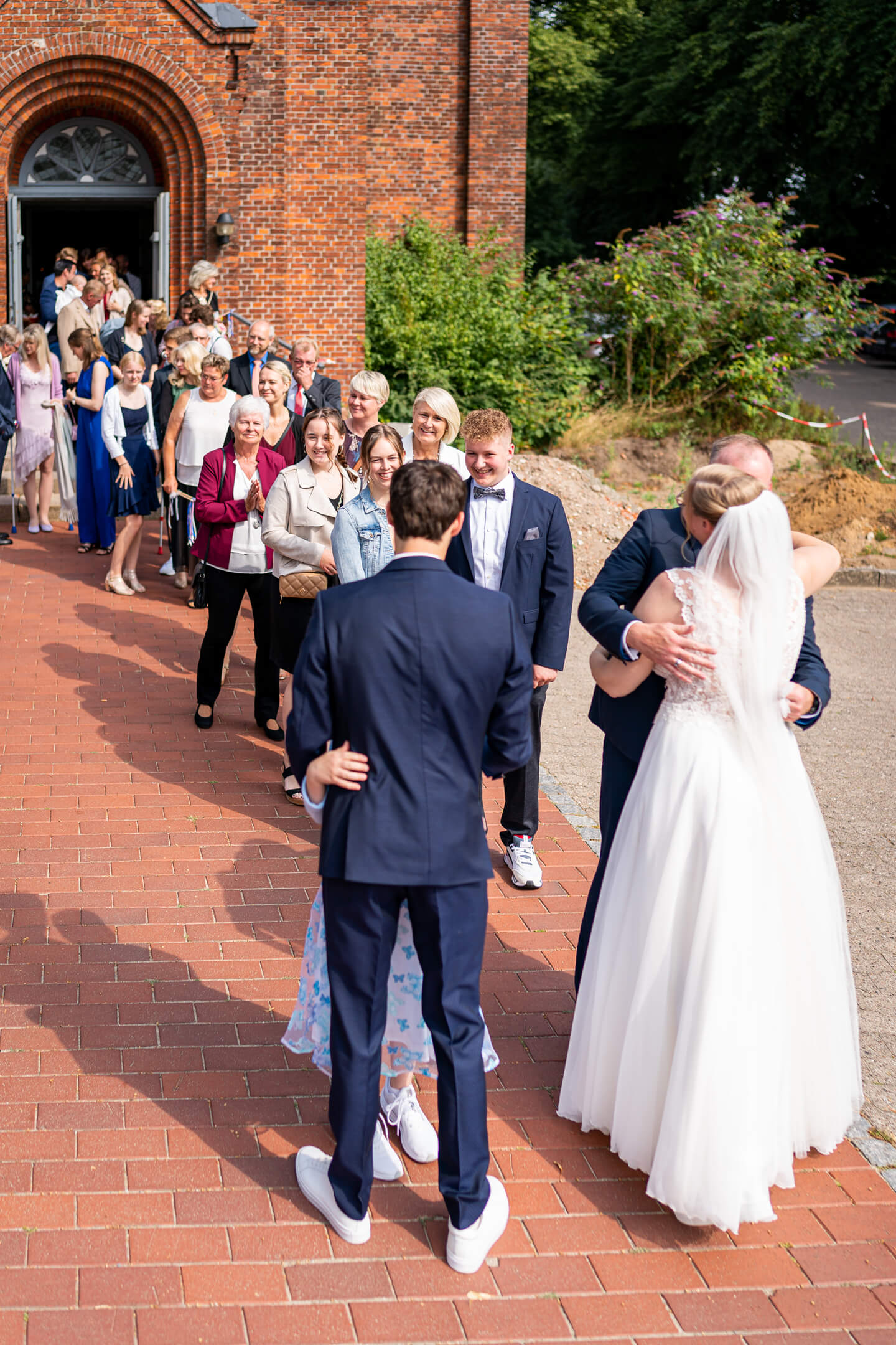Hochzeitsgäste gratulieren vor der Kirche.