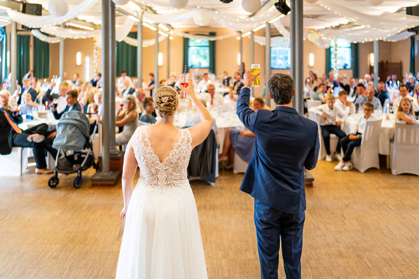 Cheers! Hochzeitspaar begrüßt die Gäste in der Location.