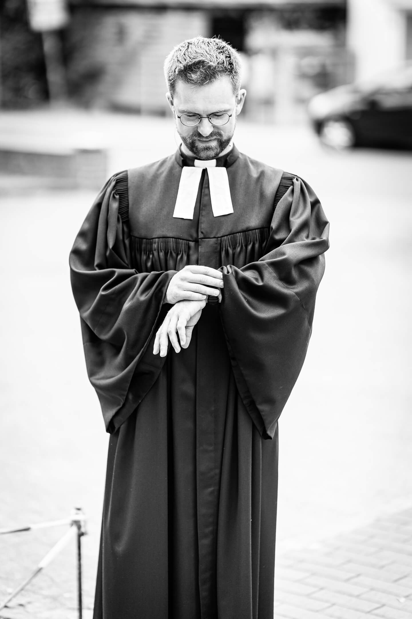 Pastor schaut auf die Uhr