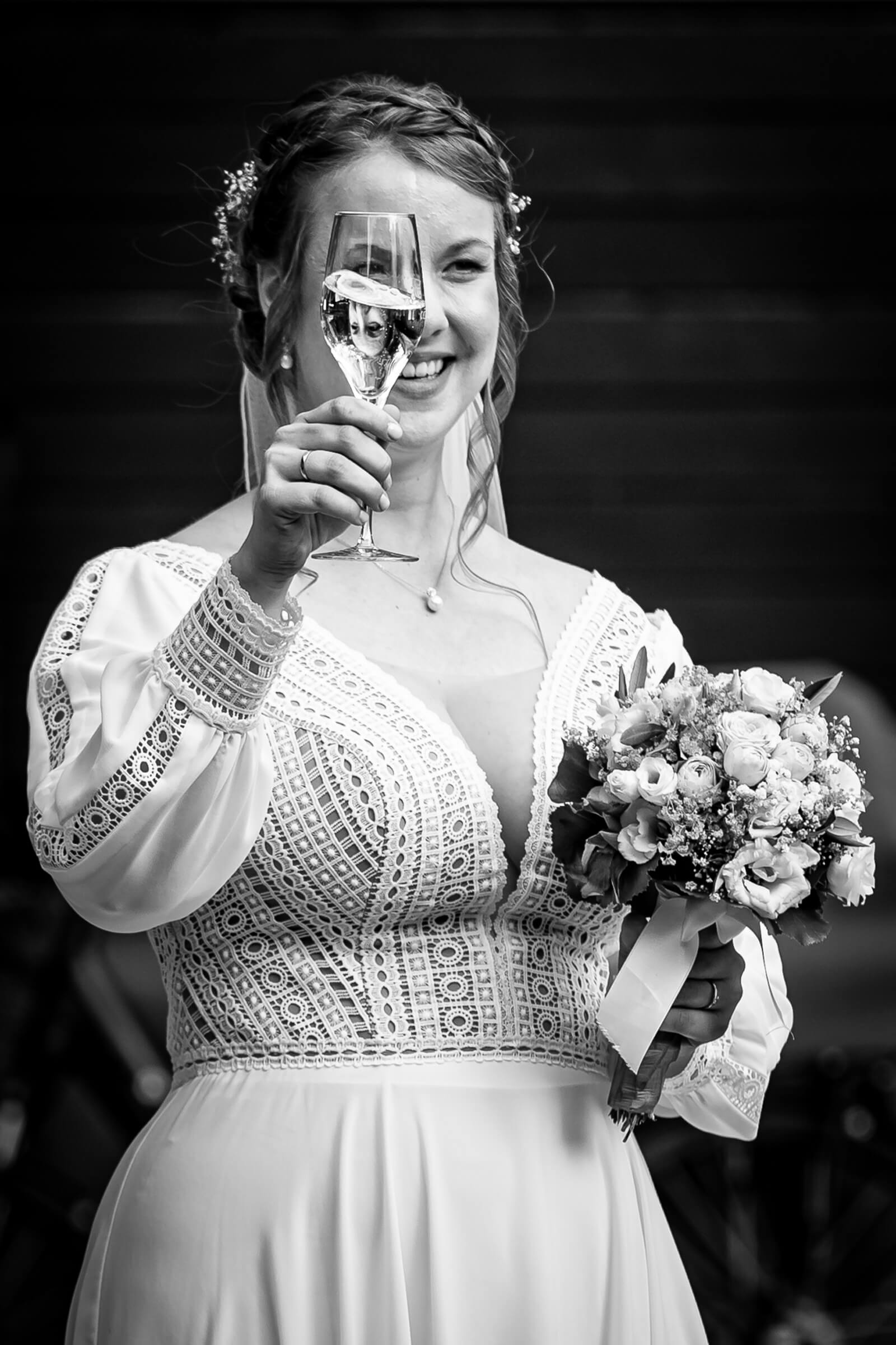 Braut prostet mit Sekt der Hochzeitsgesellschaft zu.