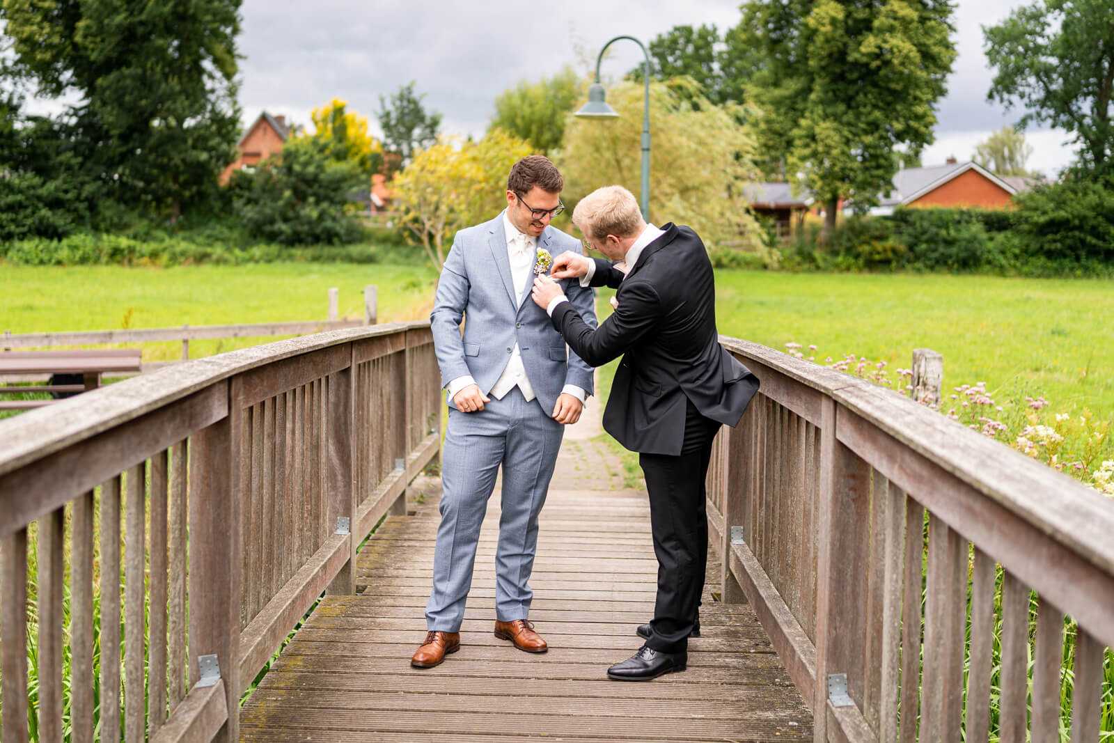 Trauzeuge steckt dem Bräutigam Blumen ans Revers