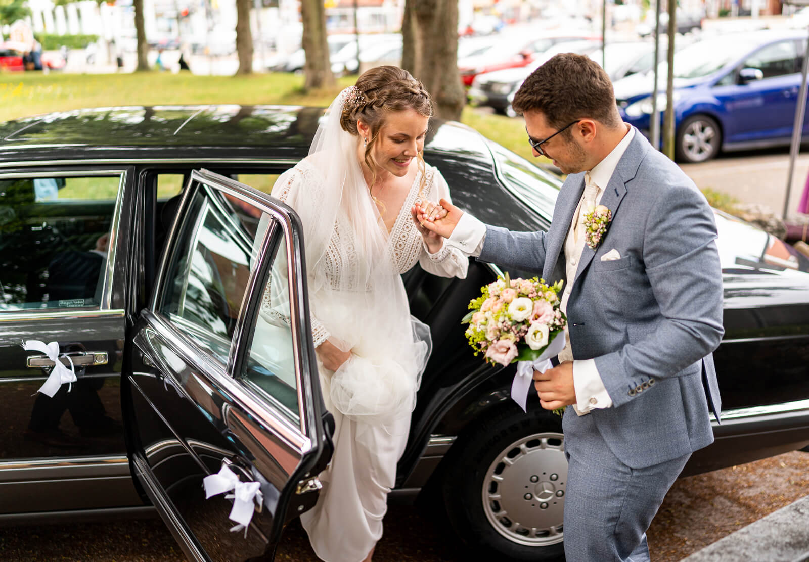 Braut steigt aus dem Hochzeitsauto aus.