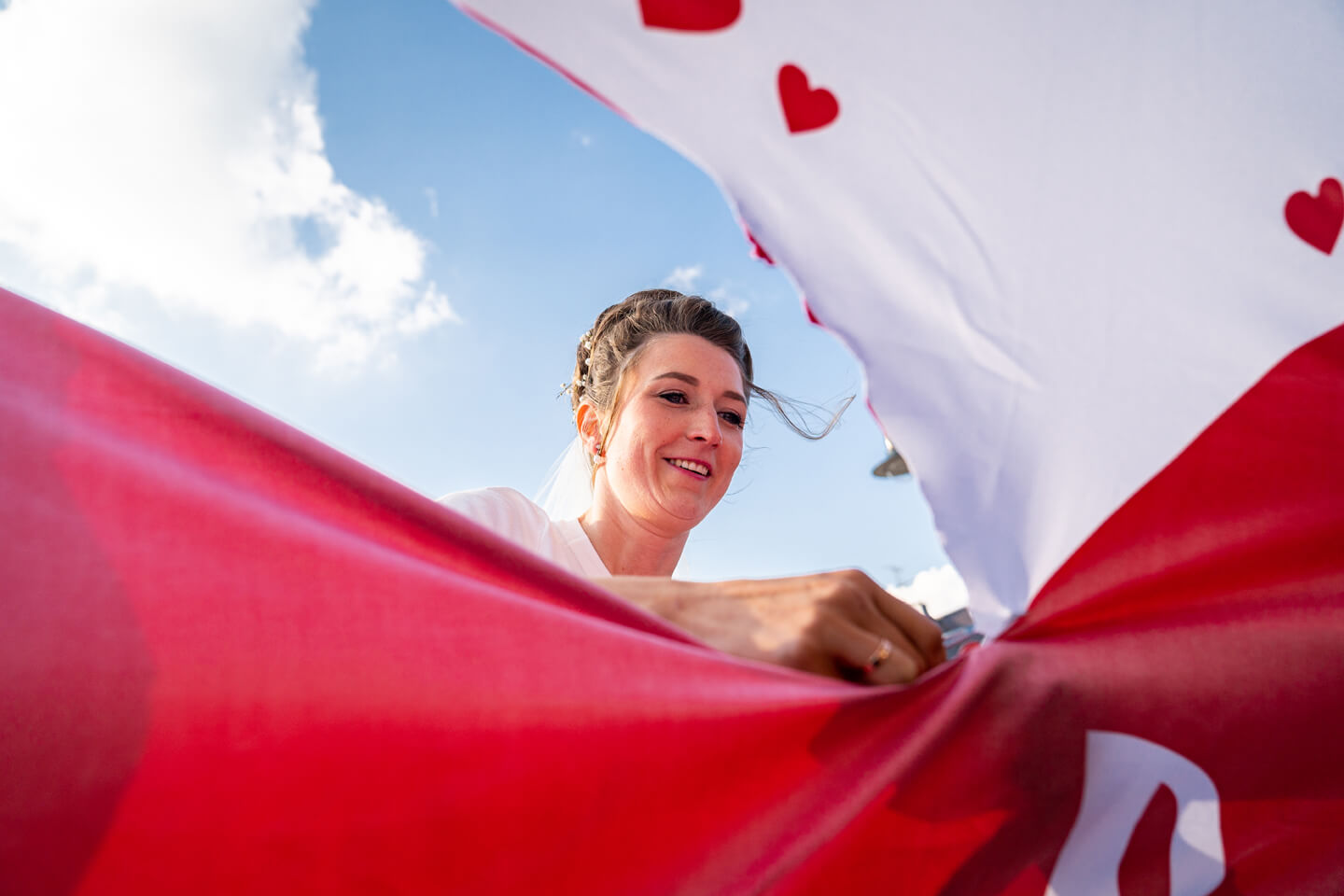 Braut schneidet mit der Nagelschere ein Herz aus dem Bettlaken.