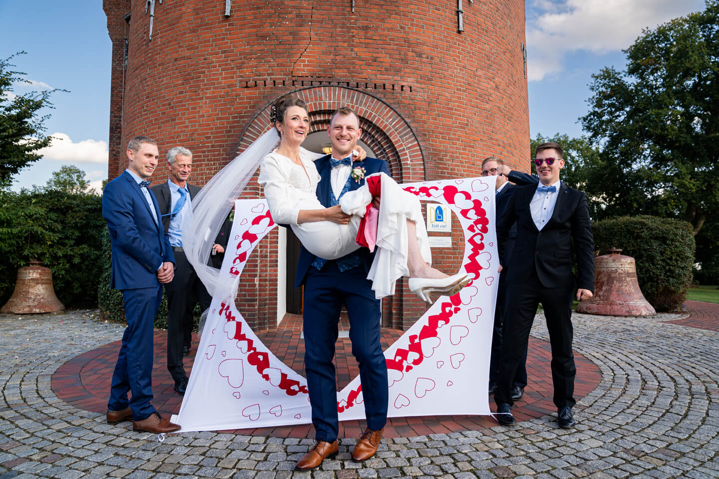 Bräutigam trägt die Braut durchs Bettlaken mit ausgeschnittenem Herz.