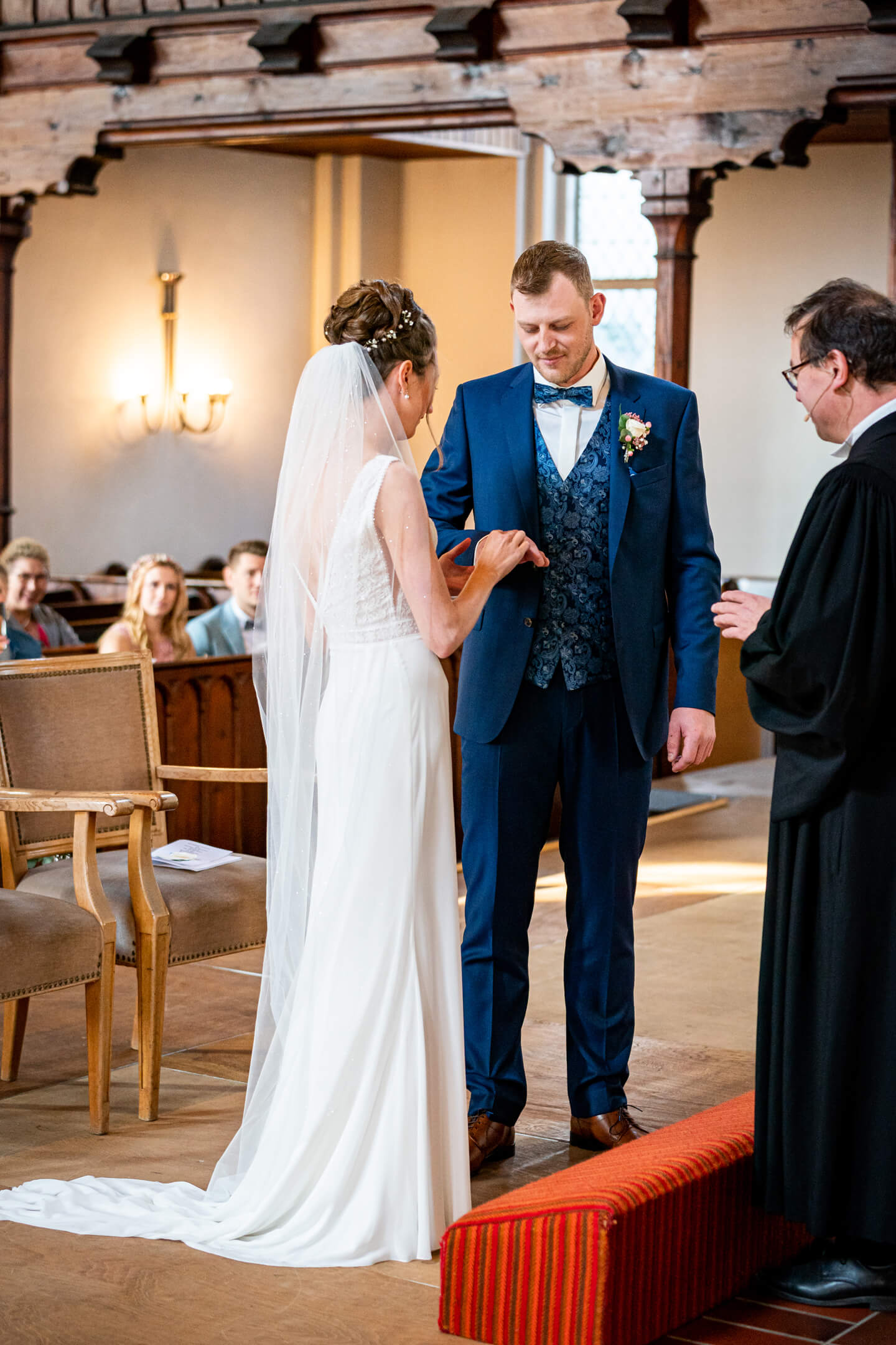 Die Braut steckt dem Bräutigam den Ring auf.