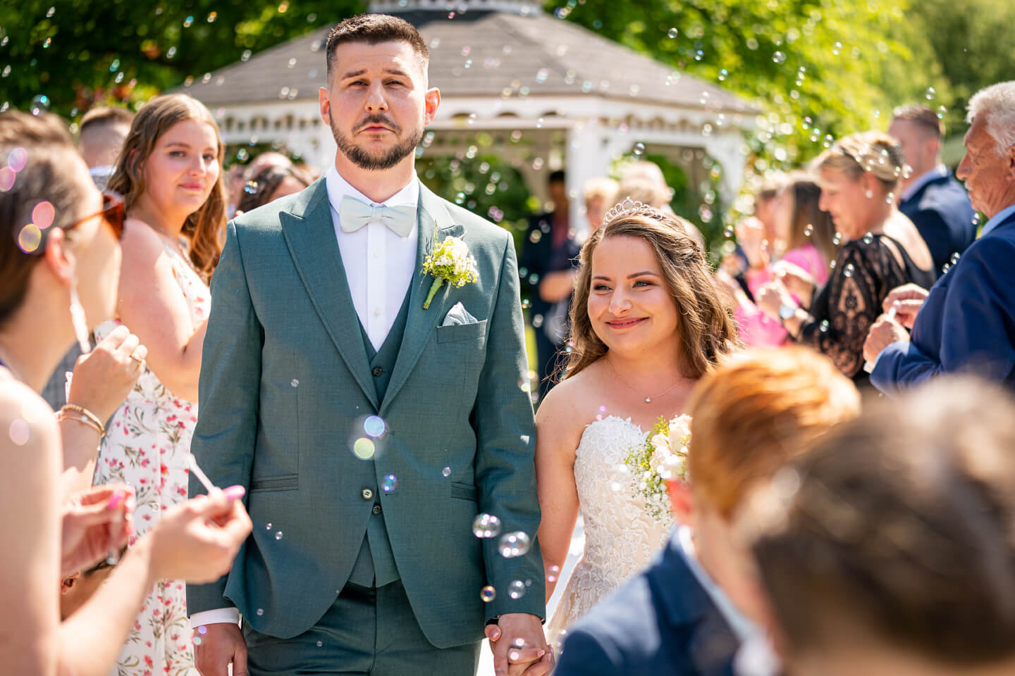 Brautpaar geht durch ein Meer von Seifenblasen nach ihrer freien Trauung.