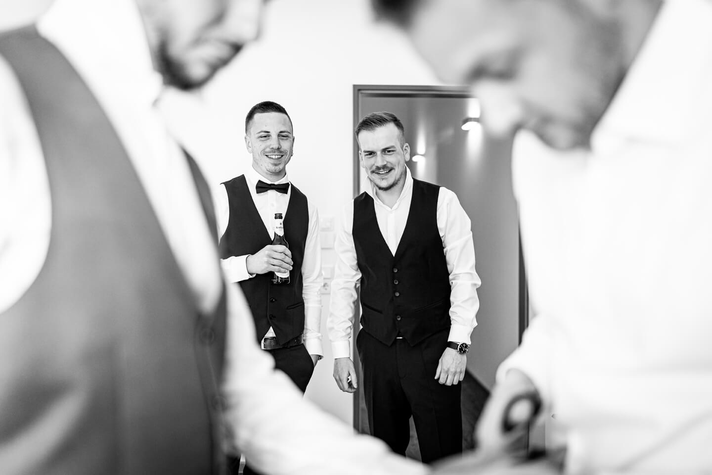 Trauzeugen blicken auf Bräutigam beim Getting Ready.