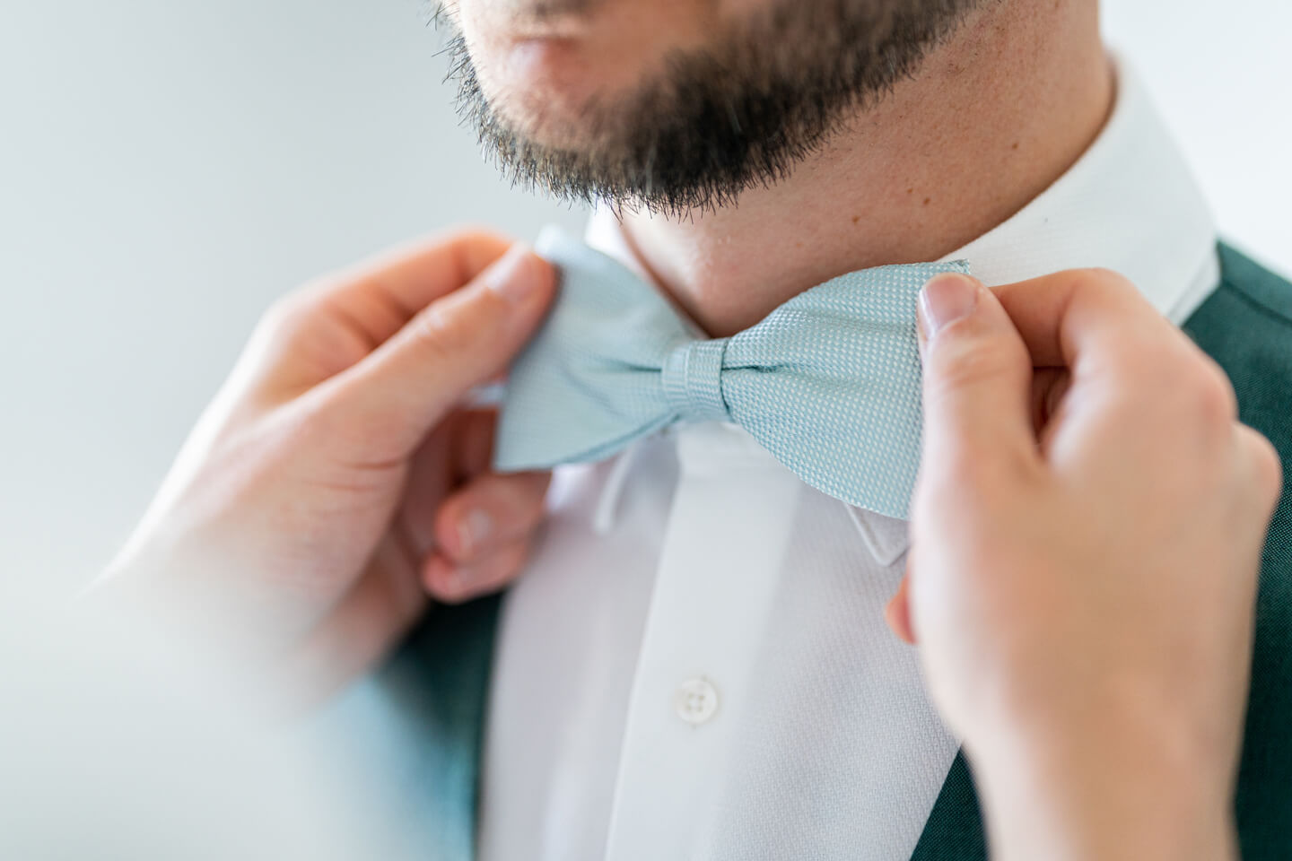 Dem Bräutigam wird die Fliege zurechtgezupft.